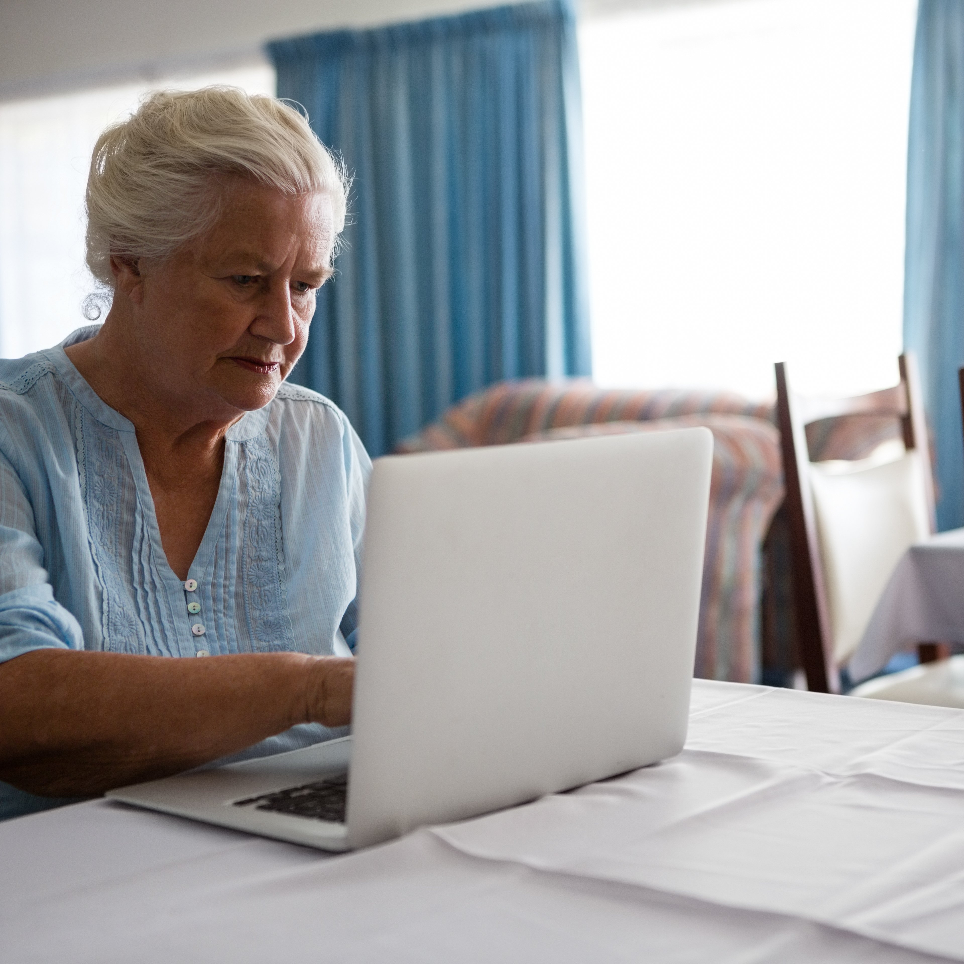 Senior woman using laptop while sitting at table in nursing home